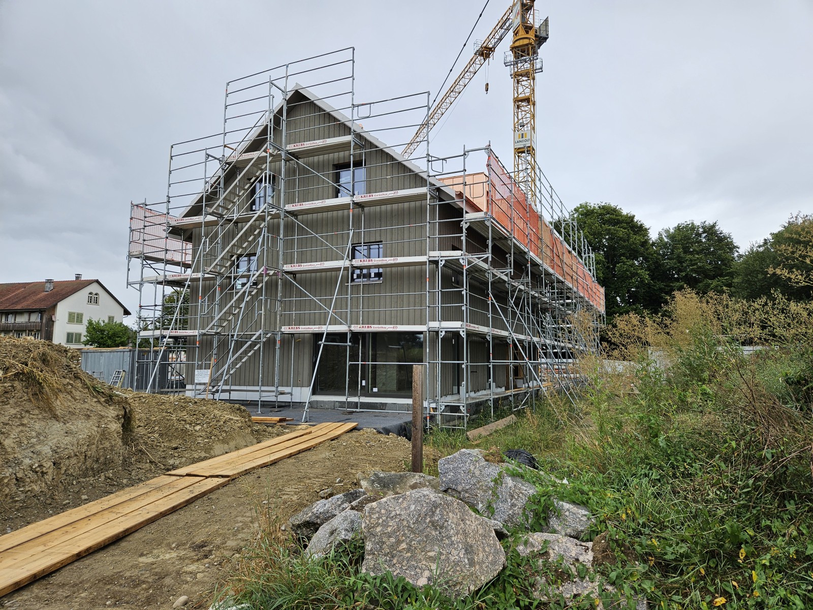 26.08.2024  Fenster und Fassadenverkleidung sind am ersten Haus montiert und Unterlagsböden gegossen